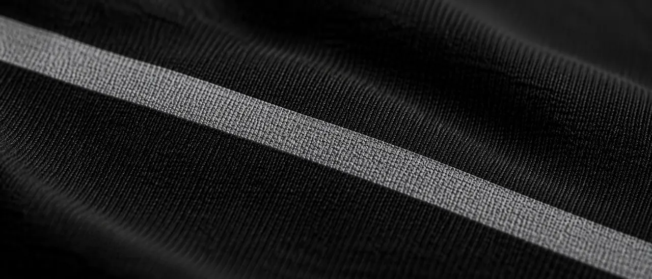 Macro photograph of a printed pale bar crossing black cotton jersey, with the weave of the fabric and the texture of the ink visible.